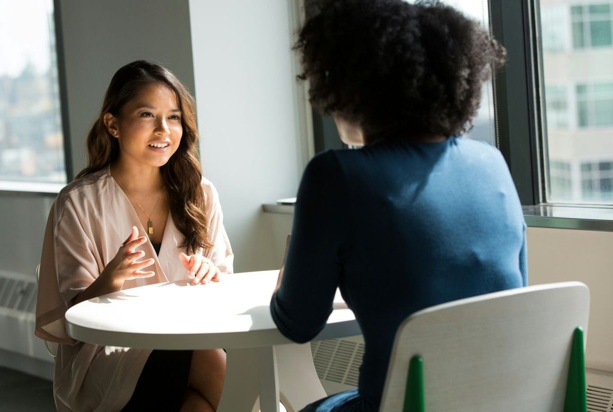 Blog 7 Tipps zu Smalltalk | Coopers Group Zwei Frauen unterhalten sich an einem runden Tisch.