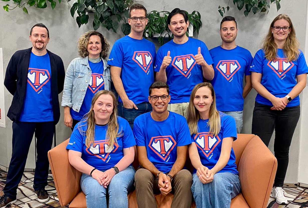 Menschen mit gleichem T-Shirt in Königsblau stehen und sitzen für ein Gruppenfoto zusammen